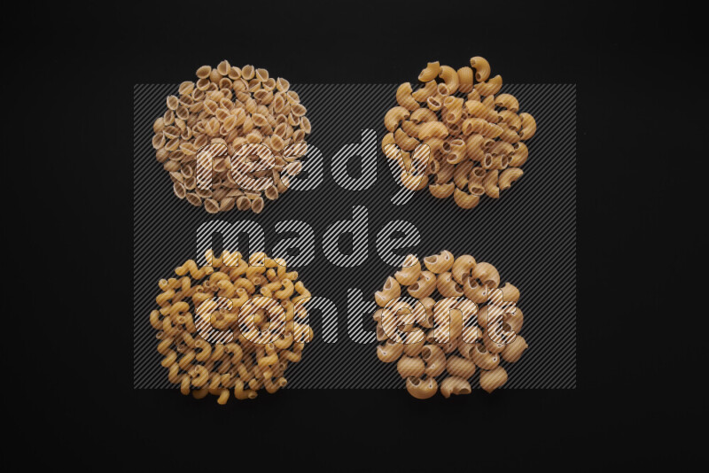 Different pasta types in bunches on black background