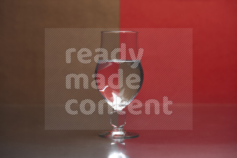 The image features a clear glassware filled with water, set against brown and red background