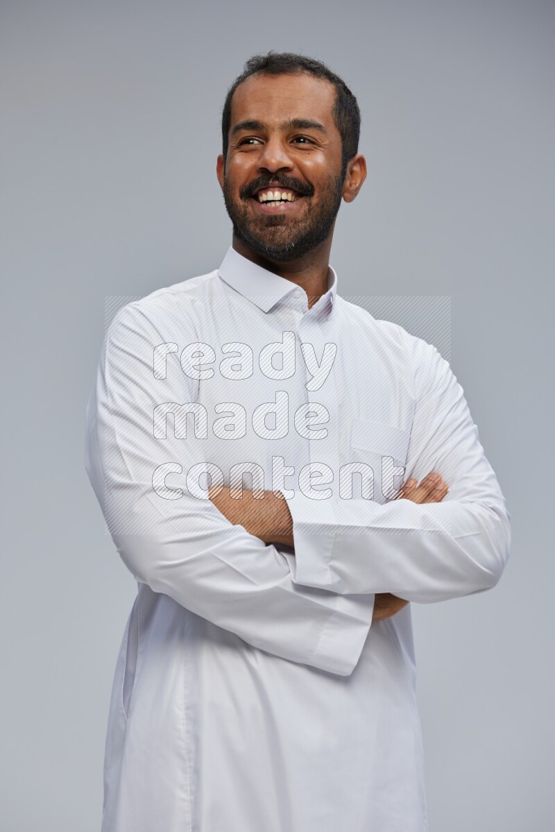Saudi man wearing Thob standing with crossed arms on Gray background