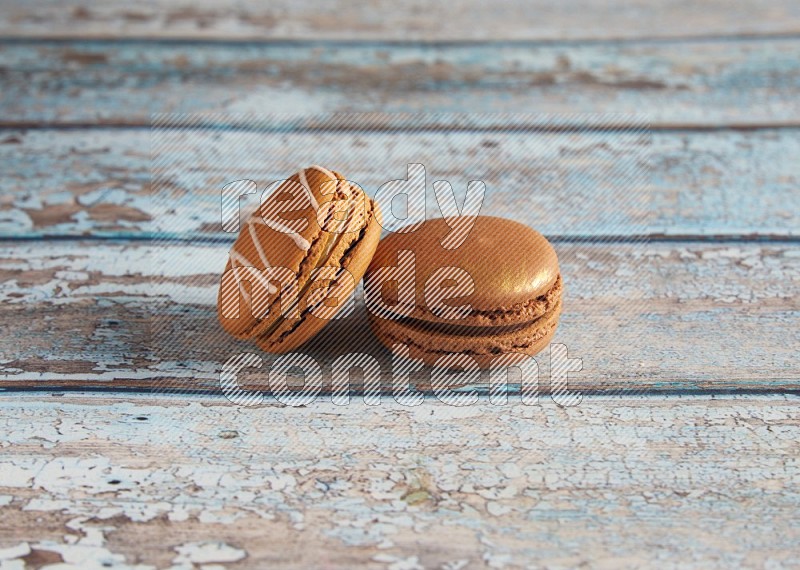 45º Shot of of two assorted Brown Irish Cream, and Brown Coffee macarons on light blue background