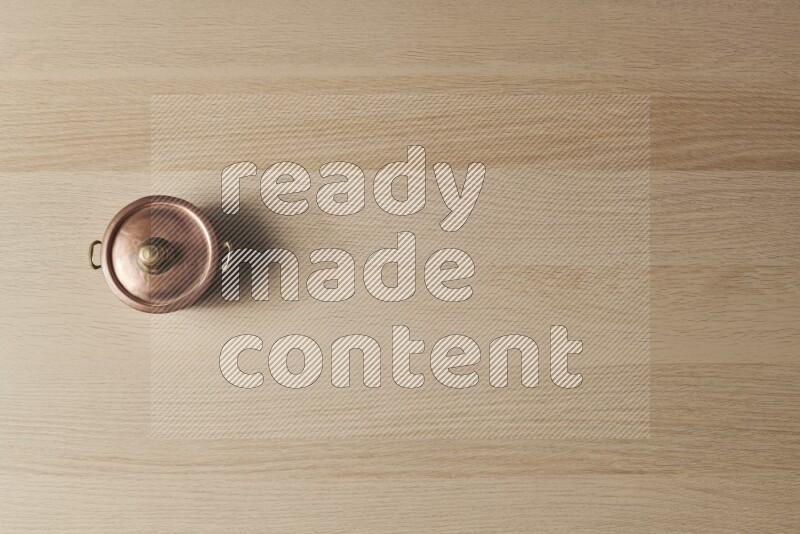 A small copper pot on light wooden background