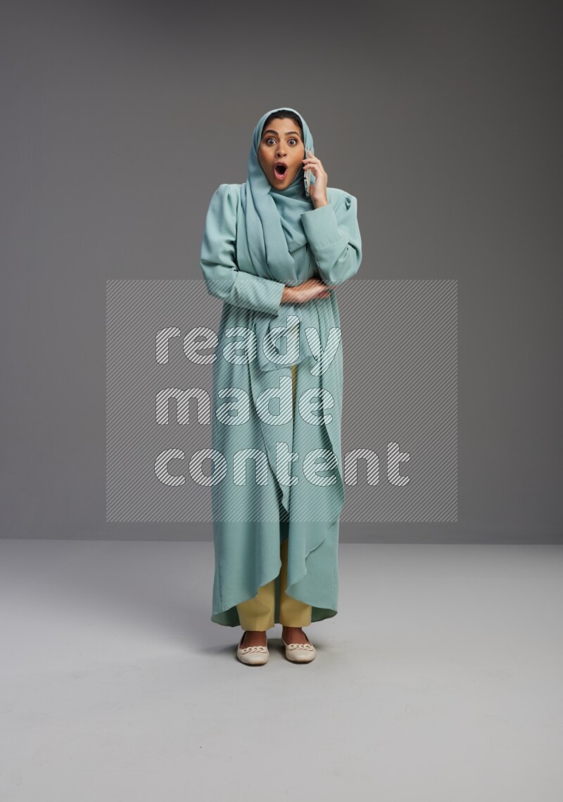 Saudi Woman wearing Abaya standing talking on phone on Gray background