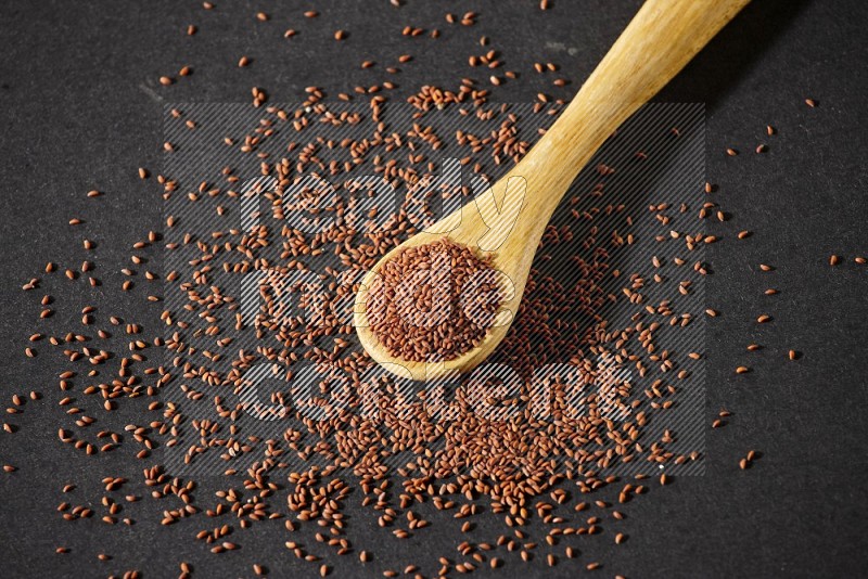 A wooden spoon full of garden cress and seeds spreaded beside it on a black flooring in different angles