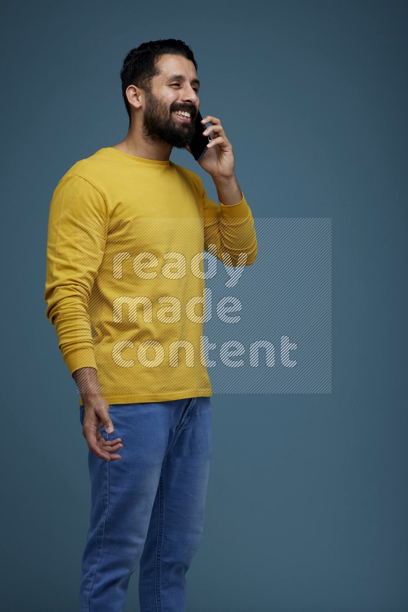 A man having a calling in a blue background wearing a yellow shirt