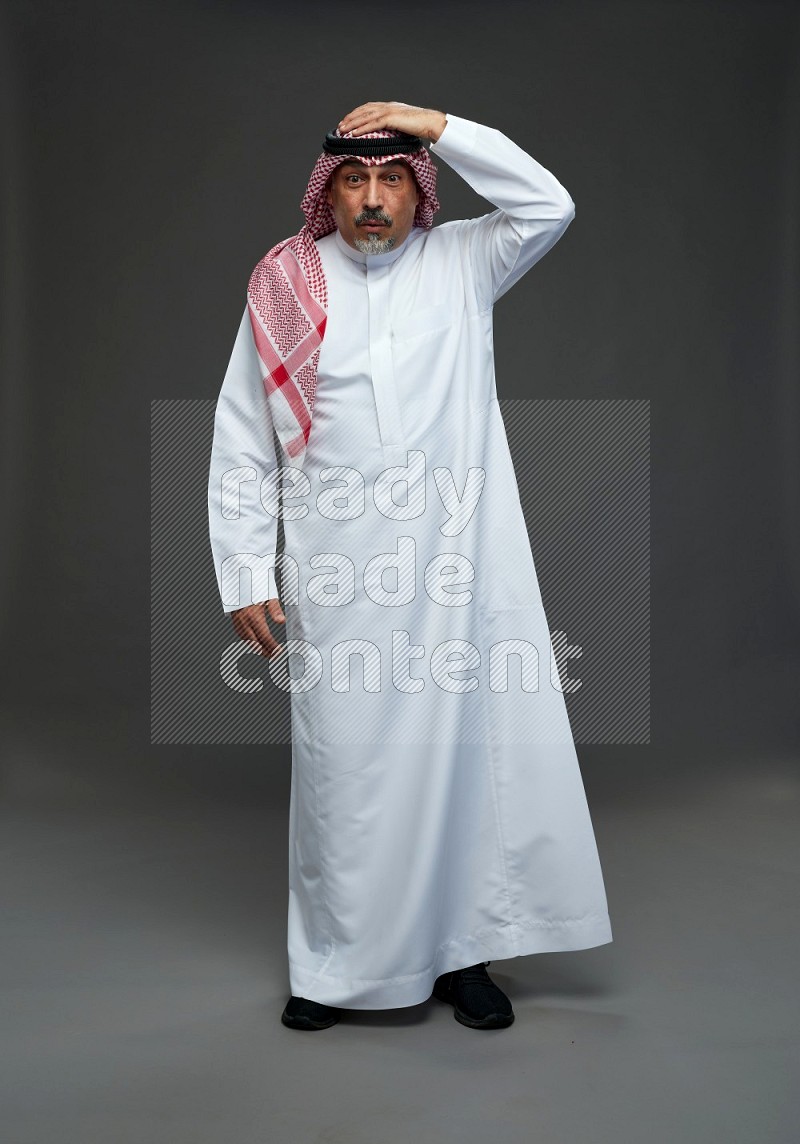 Saudi man with shomag Standing Interacting with the camera on gray background