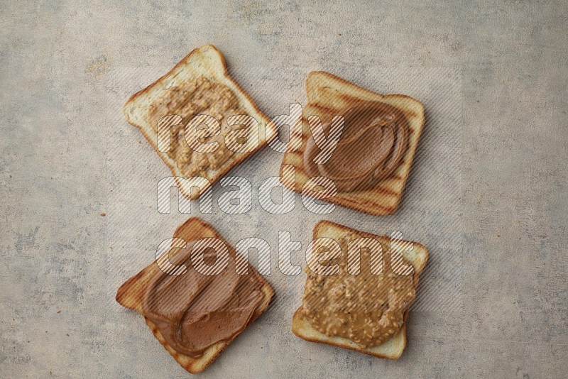 Creamy and crunchy peanut butter on a toasted white toast slices on a light blue textured background