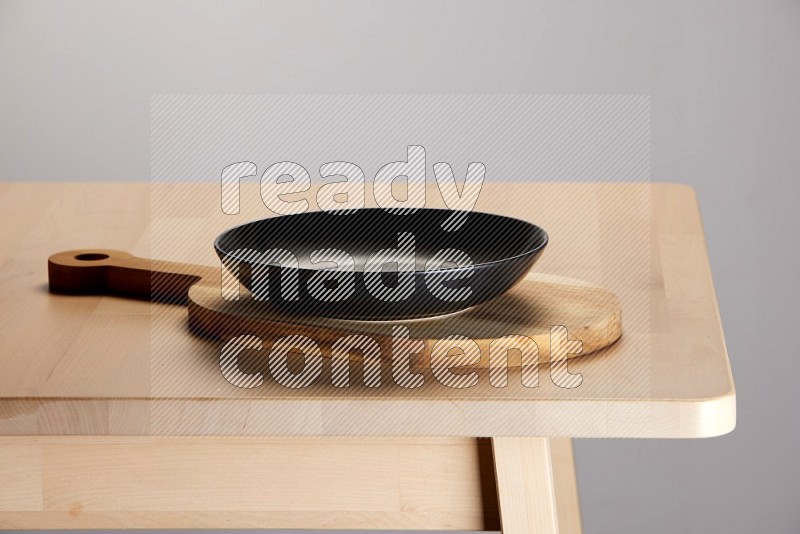 black plate placed on a  wooden oval cutting board on the edge of wooden table
