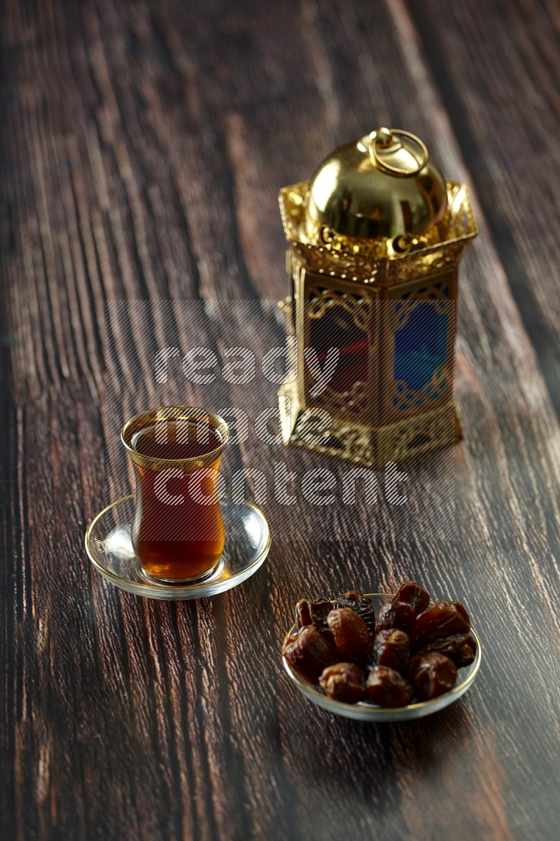 A golden lantern with different drinks, dates, nuts, prayer beads and quran on brown wooden background