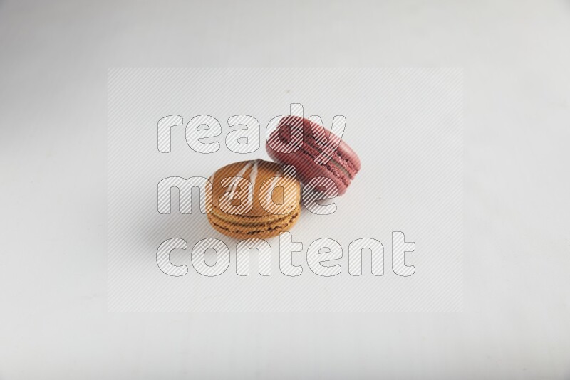 45º Shot of of two assorted Brown Irish Cream, and Red Velvet macarons on white background