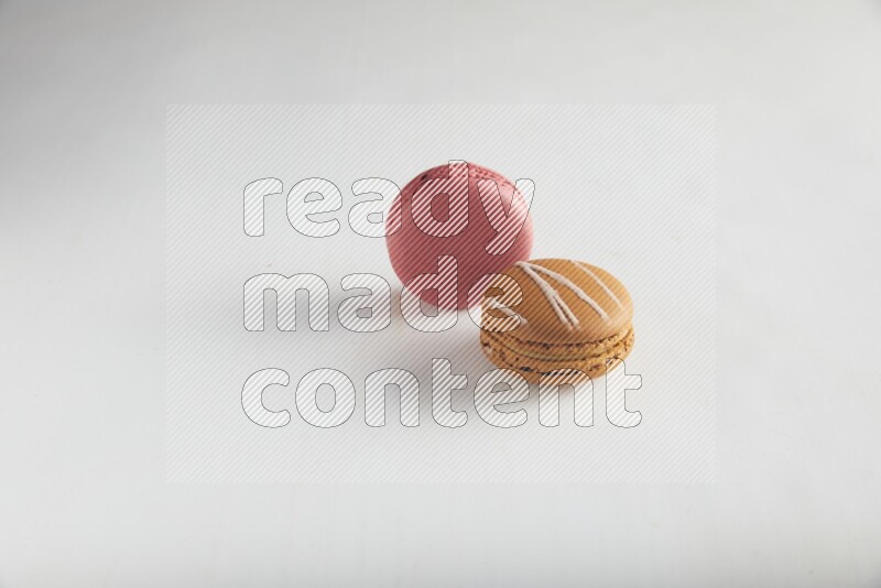 45º Shot of of two assorted Brown Irish Cream, and Pink Raspberry macarons on white background