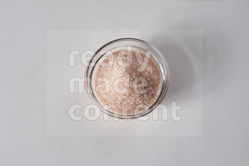 A glass bowl full of fine himalayan salt on white background