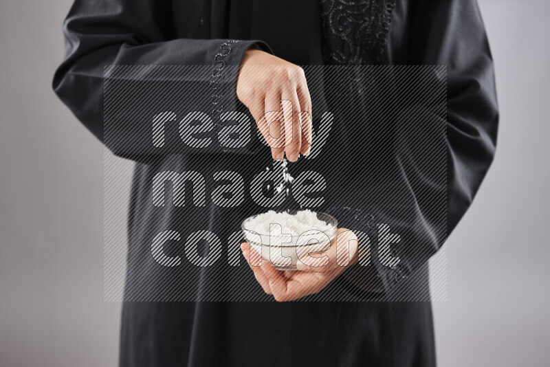 Woman in abaya holding different kinds of spices in different positions