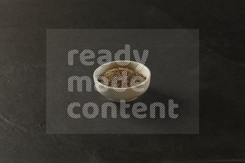 white ceramic round sauce bowl filled with herbs on grey textured countertop