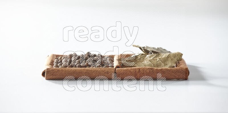 2 squares of cinnamon sticks full of allspice and bay laurel leaves on white flooring