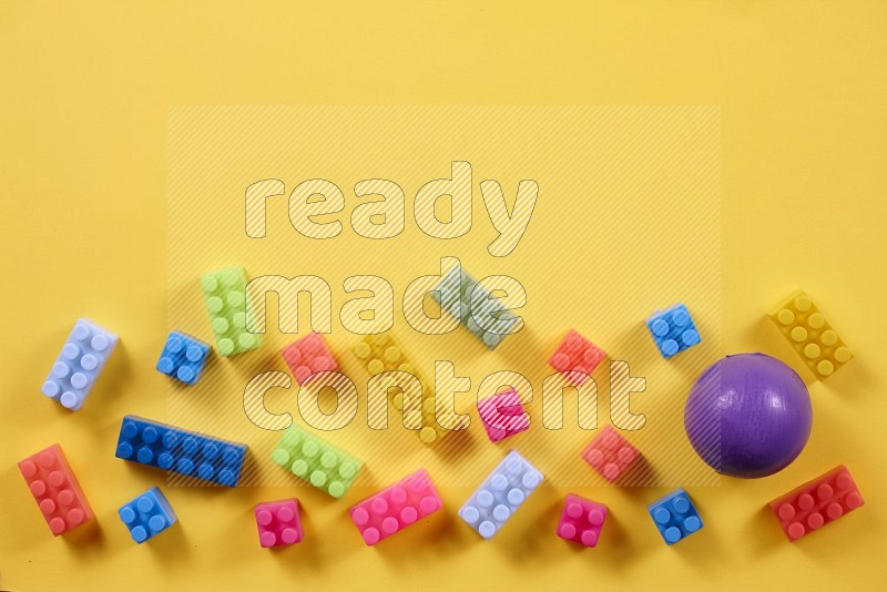 Plastic building blocks with balls on yellow background in top view (kids toys)