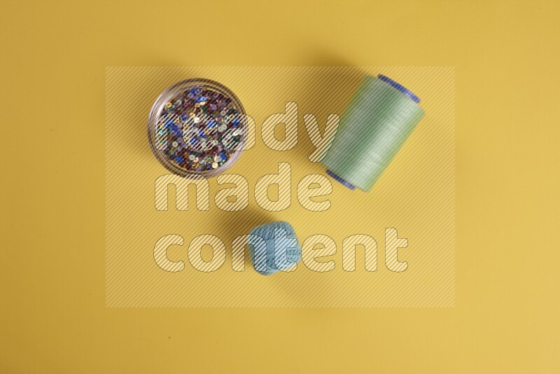 مجموعة من أدوات الخياطة والتفصيل خضراء اللون على خلفية صفراء