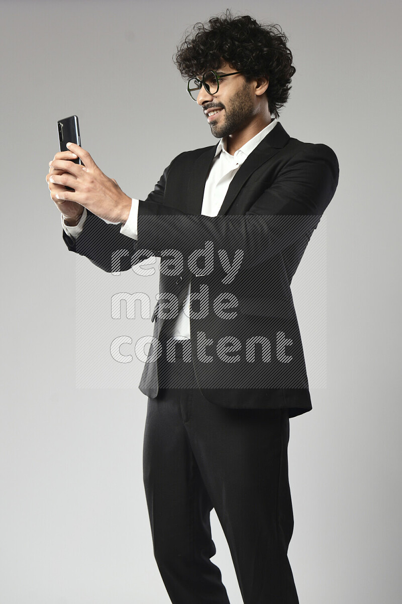 A man wearing formal standing and taking a selfie on white background