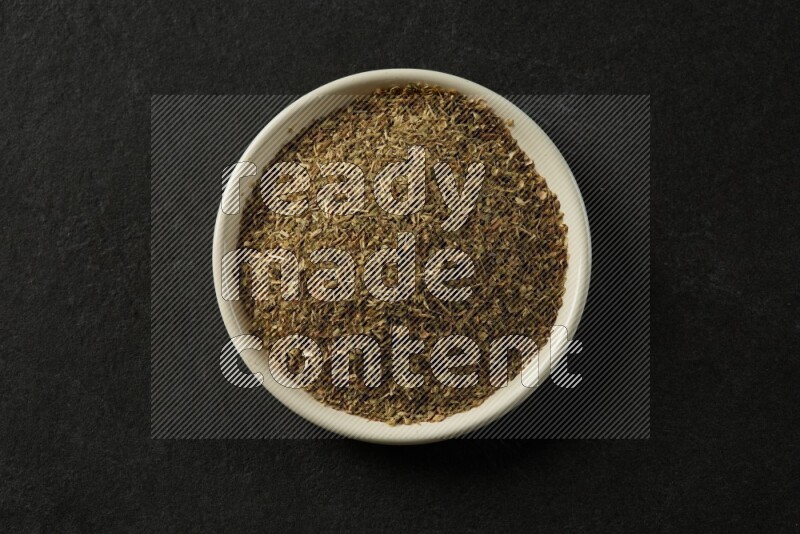 white ceramic round sauce dish filled with herbs on grey textured countertop