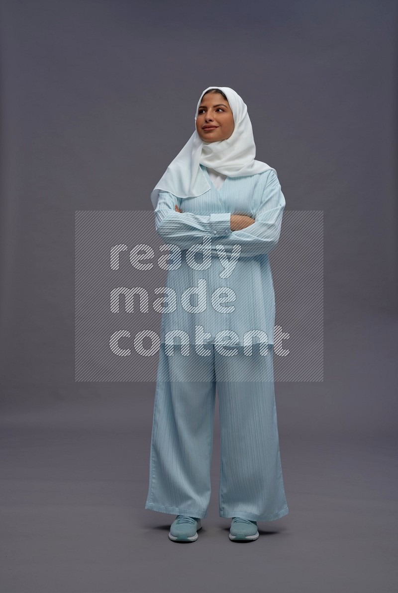 Saudi woman wearing hijab clothes standing with crossed arms on gray background