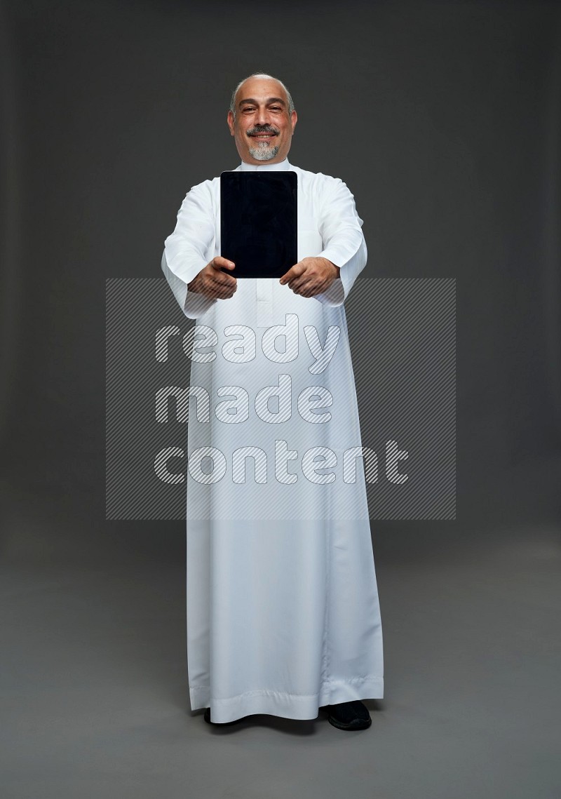 Saudi man without shomag Standing working on tablet on gray background