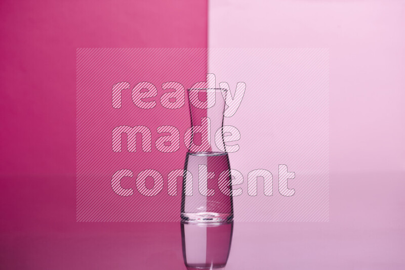 The image features a clear glassware filled with water, set against pink background