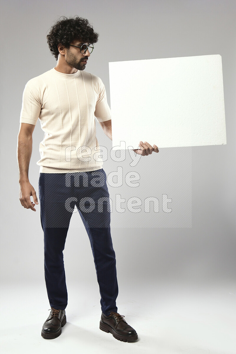 A man wearing casual standing and holding a white board on white background