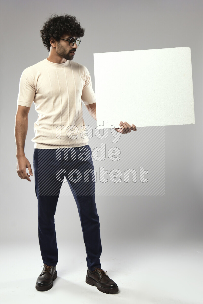 A man wearing casual standing and holding a white board on white background
