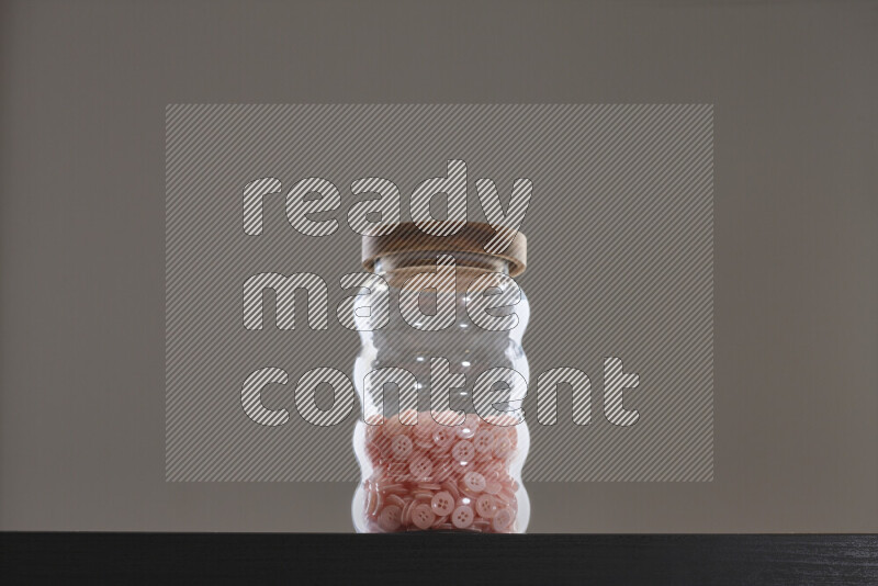 أزرار متنوعة في وعاء زجاجي علي خلفية سوداء