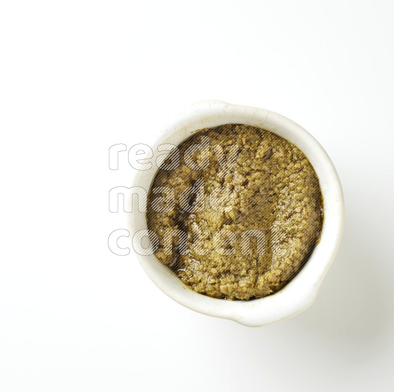 medium off white pottery round bowl filled with pesto paste on a white counter top