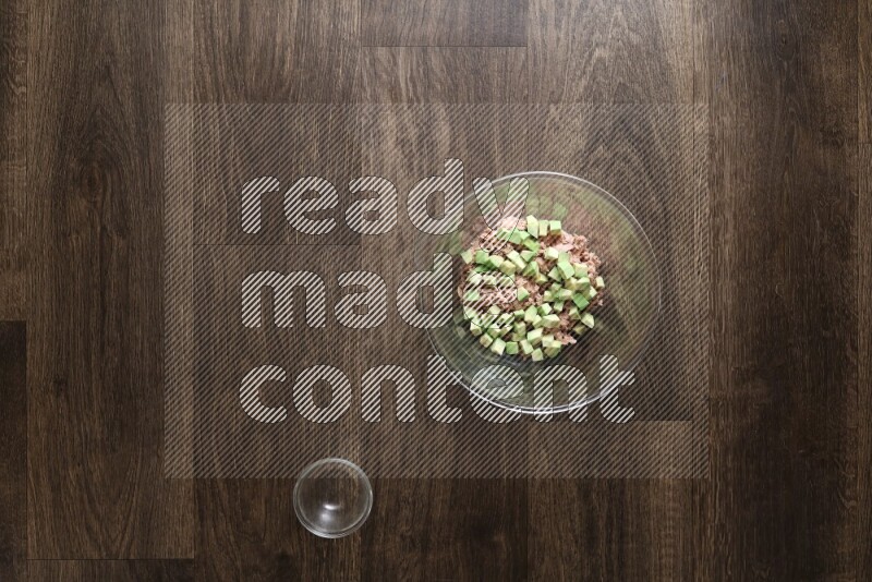 A glass bowl full of tuna, avocado, mango, blackberry and strawberry on wooden background