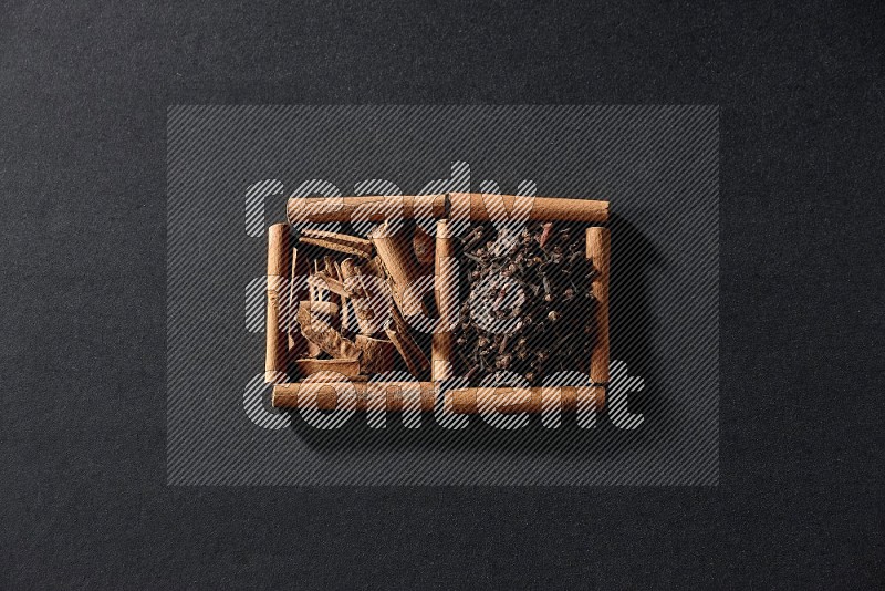 2 squares of cinnamon sticks full of cloves and cinnamon on black flooring