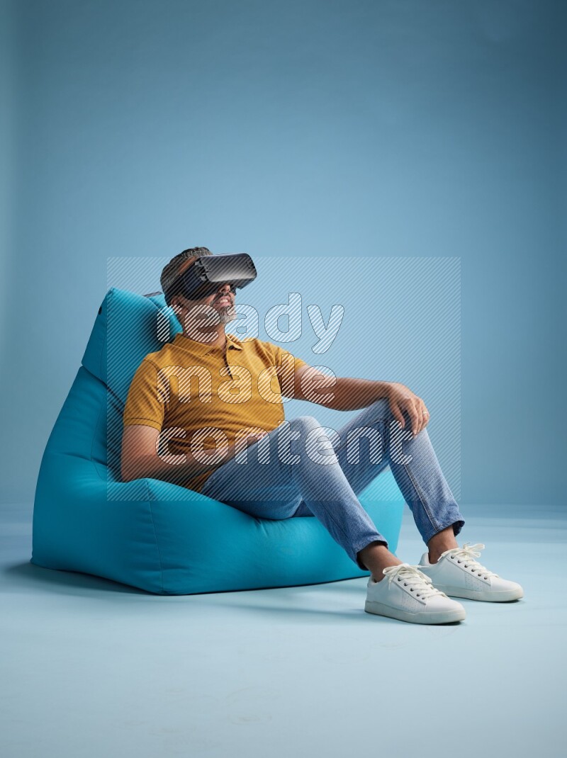 A man sitting on a blue beanbag and gaming with VR