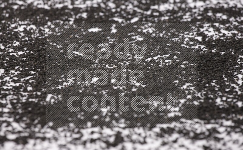 Black seeds spread on a white flooring