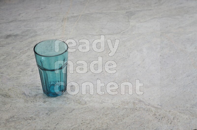 A turquoise glass cup on grey marble background