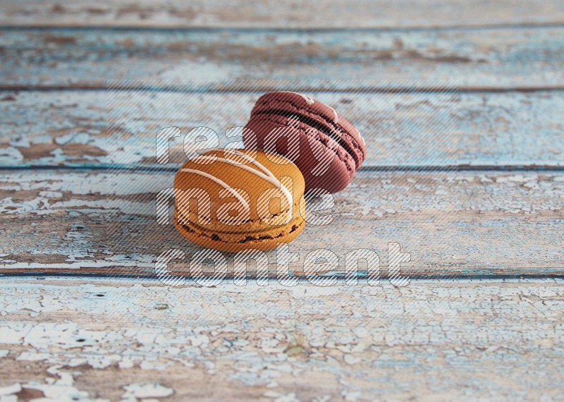 45º Shot of of two assorted Brown Irish Cream, and Red Poppy Flower macarons  on light blue background