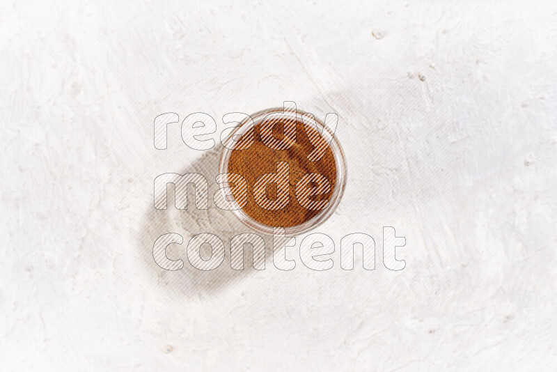 A glass jar full of ground paprika powder on white background