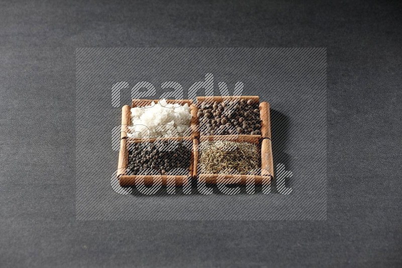4 squares of cinnamon sticks full of black pepper, cumin, allspice and white salt on black flooring