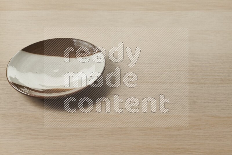 A multicolored pottery plate on light wooden background