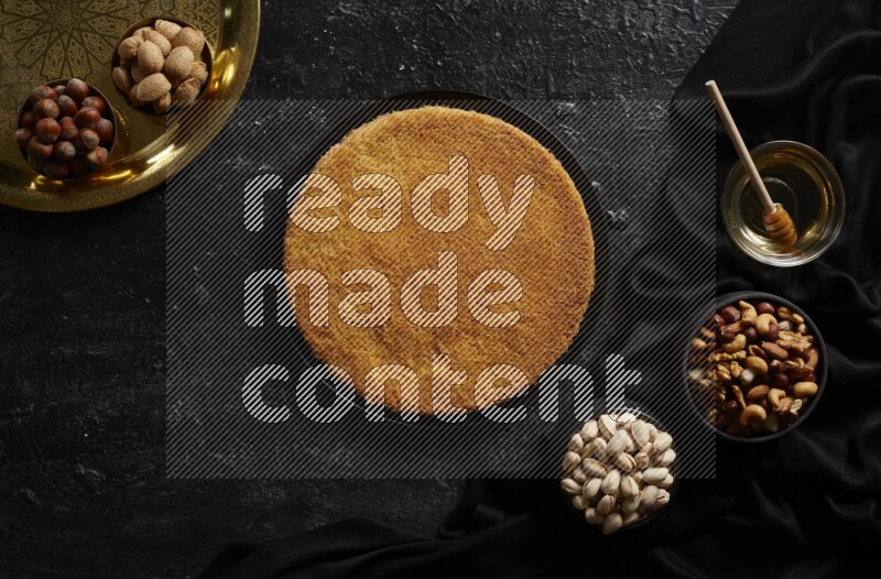 Konafa with nuts and honey in a dark setup