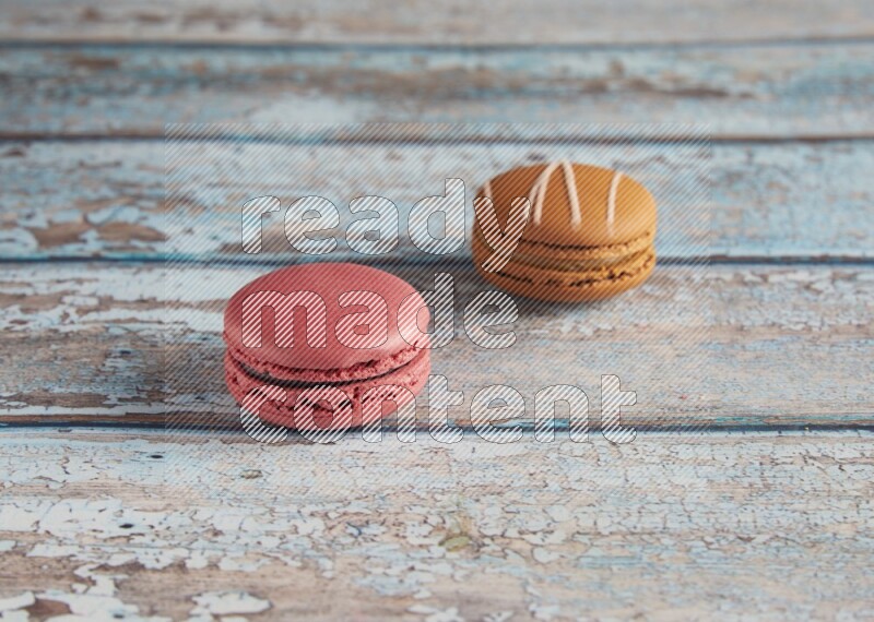 45º Shot of of two assorted Brown Irish Cream, and Pink Raspberry macarons on light blue background