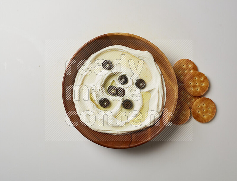 Lebnah garnished with sliced olives in a wooden plate on a white background