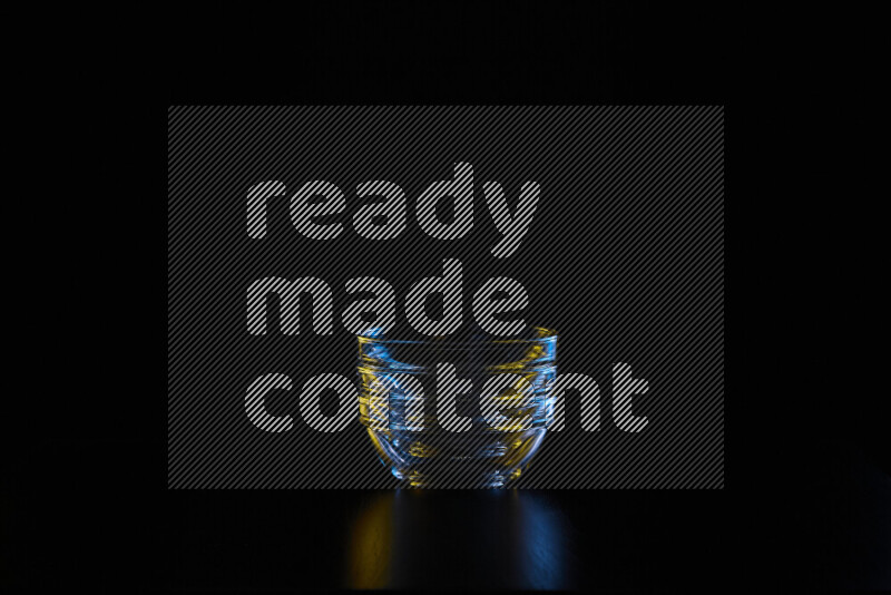 Glassware with rim light in blue and yellow against black background