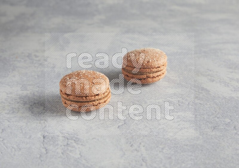 45º Shot of two Brown Hazelnuts macarons  on white  marble background