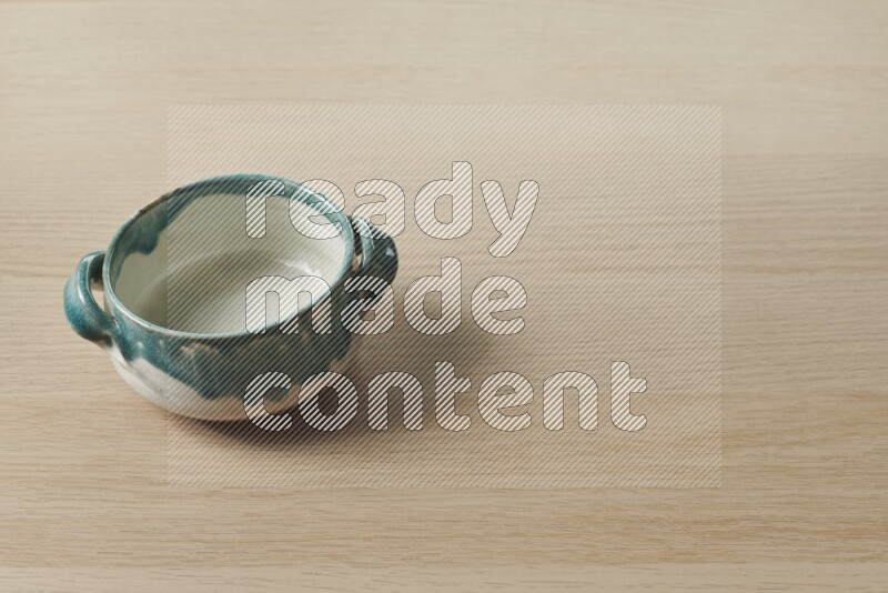 A multicolored pottery bowl on light wooden background