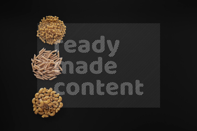 Different pasta types in 3 bunches on black background