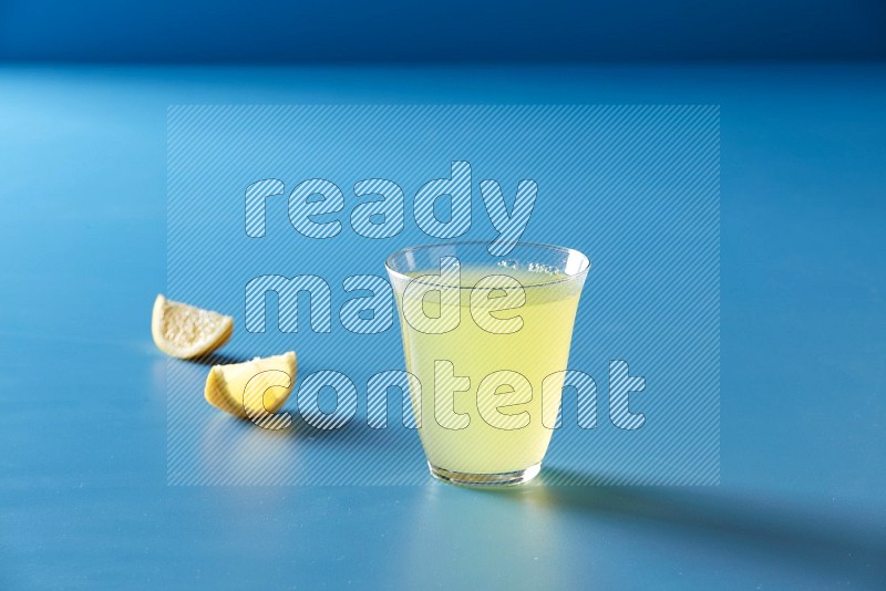 glass of lemon juice on blue background