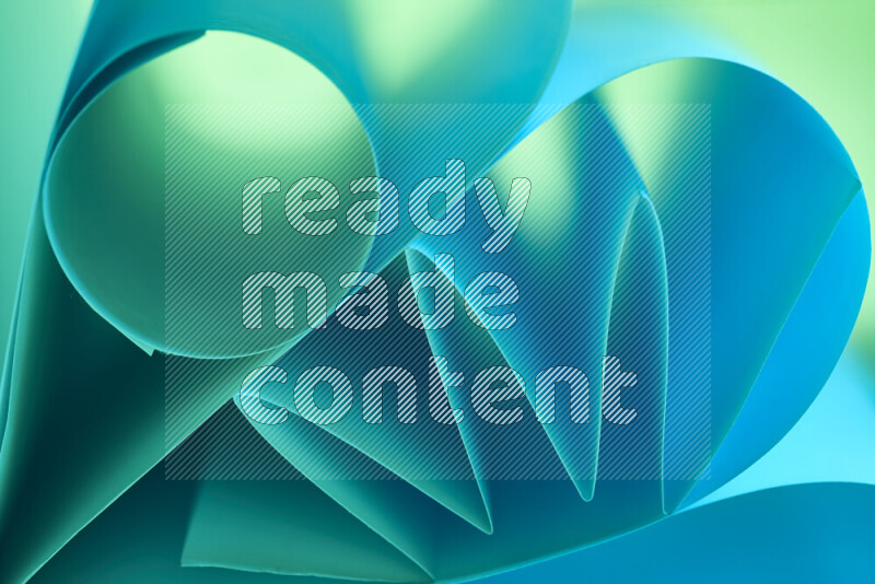 An artistic display of paper folds creating a harmonious blend of geometric shapes, highlighted by soft lighting in green and blue tones