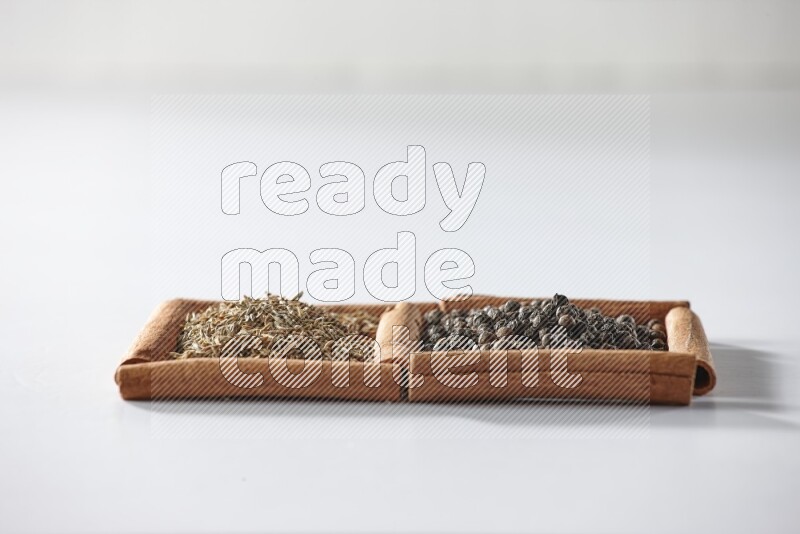 2 squares of cinnamon sticks full of black peppers and cumin on white flooring