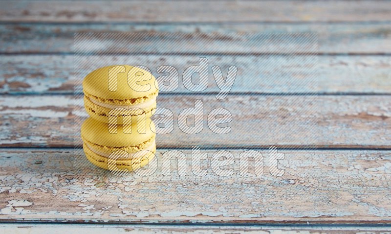 45º Shot of two Yellow Lime macarons on light blue wooden background