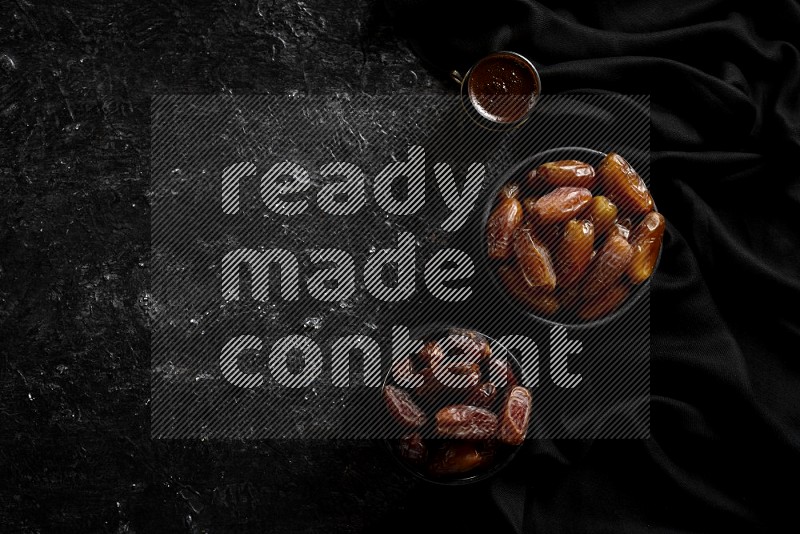 Dates in pottery bowls with coffee in a dark setup